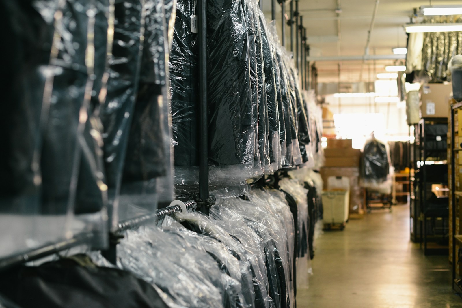 Dry-cleaned garments in protective covers on a long rail